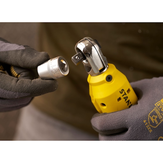 Photo of STANLEY SFMCF930B cordless ratchet held by gloved hands, close-up showing socket attachment.