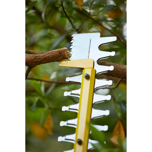 STANLEY SFMCHT855M1 hedge trimmer blade close-up cutting a tree branch outdoors.