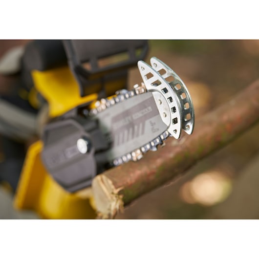 STANLEY SFMCPS415B chainsaw cutting a tree branch, close-up angle, yellow and black body visible.
