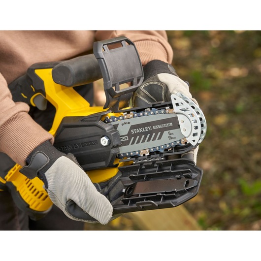 STANLEY SFMCPS415B chainsaw close-up in use, showing chain and protective gloves outdoors.