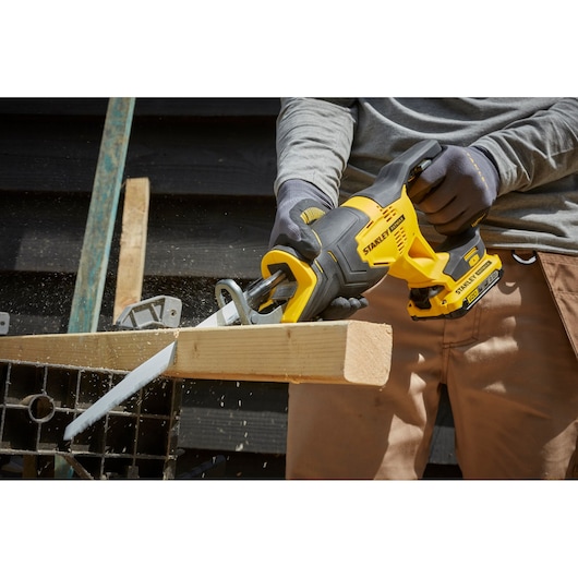 STANLEY SFMCS300D2K reciprocating saw in use cutting wood, close-up side view, yellow and black cordless tool.