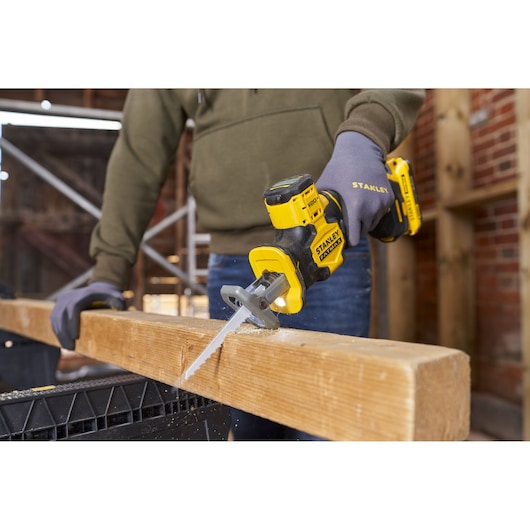 Photo of STANLEY SFMCS305B cordless reciprocating saw cutting wood beam on construction site.