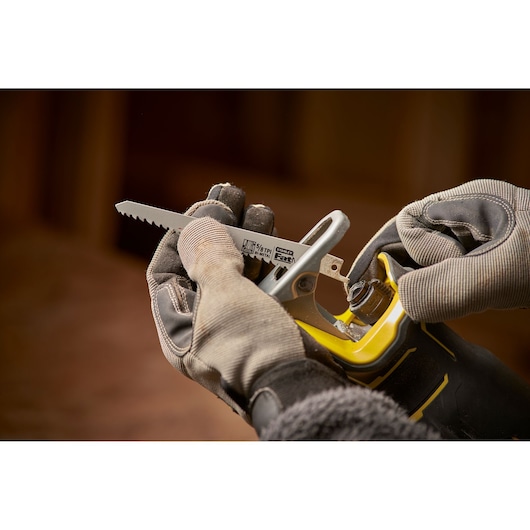Stanley SFMCS310D2K reciprocating saw being fitted with a blade, close-up, yellow and black handle.