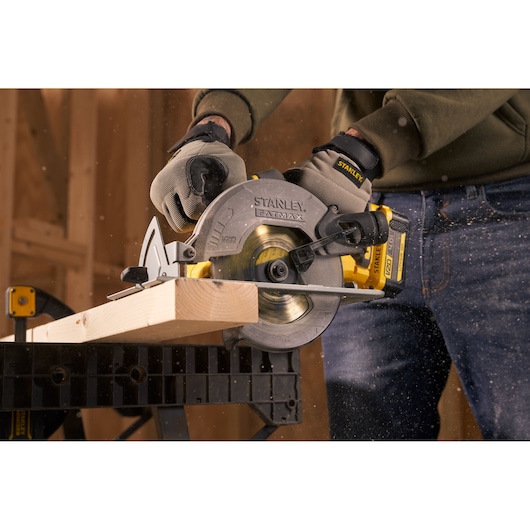 STANLEY SFMCS500B circular saw cutting wood, close-up side angle, worker wearing gloves.
