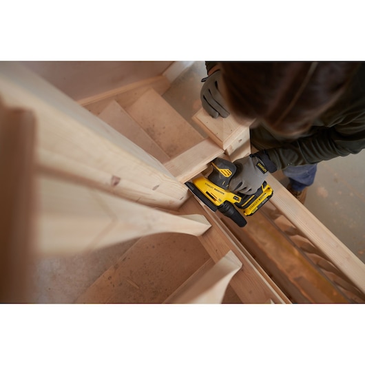 STANLEY SFMCW221D1S cordless sander used on wooden stairs, shown in action from above.