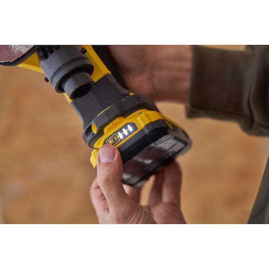 STANLEY SFMCW221D1S yellow cordless tool close-up showing battery indicator, hand pressing button.