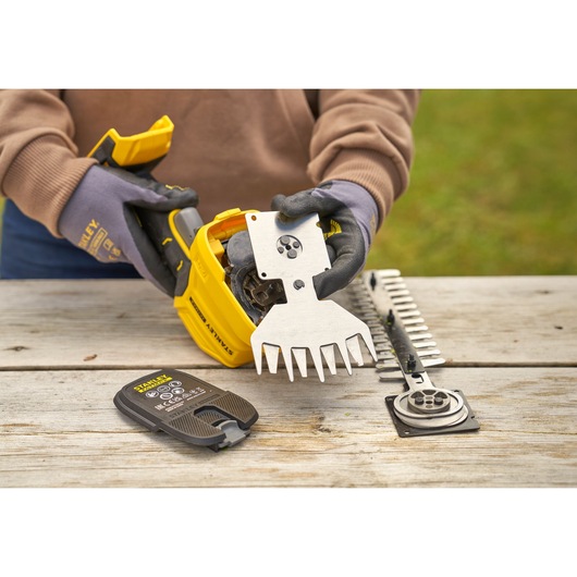 STANLEY STCSS20B garden tool with metal blade attachment and battery on wooden table, close-up.