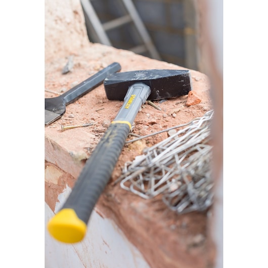 STANLEY STHT0-51910 sledge hammer with black head and yellow-gray handle on construction site.