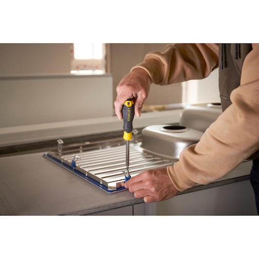 Photo of STANLEY STHT0-70885 screwdriver used to fasten metal brackets on a kitchen sink panel.
