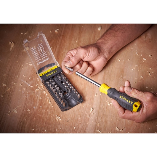 STANLEY STHT0-70885 screwdriver set with yellow and black handle and multiple bits on wooden surface.