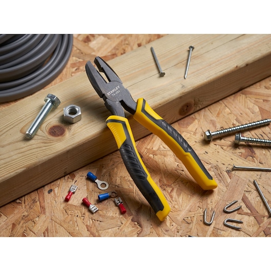 STANLEY STHT0-74454 combination pliers with yellow and black handles on a workbench with hardware.
