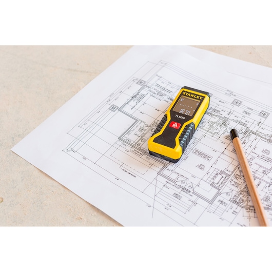 STANLEY STHT1-77409 laser distance measurer on architectural blueprint with pencil.