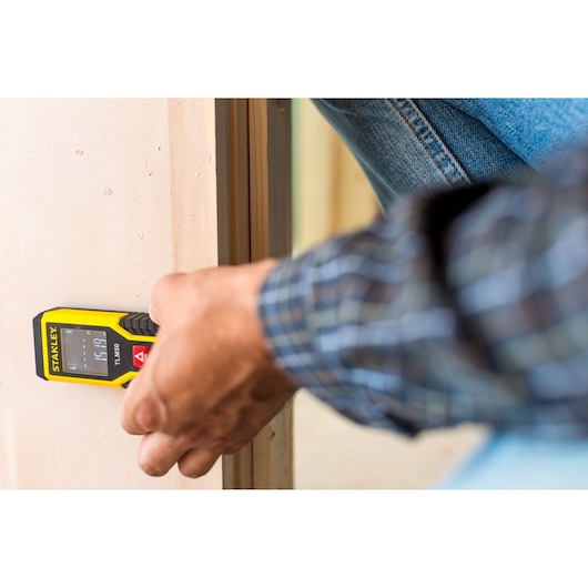 Stanley STHT1-77409 laser distance measurer in use against a wall, close-up view, Photography category.