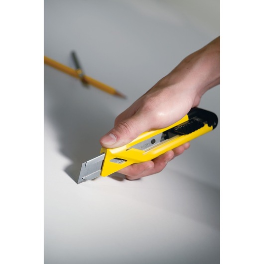 STANLEY STHT10265-0 utility knife with yellow and black handle in hand cutting white surface.