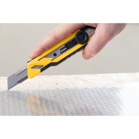 STANLEY STHT10268-0 utility knife in use cutting material, close-up angle.