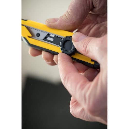 Stanley STHT10268-0 utility knife close-up showing blade adjustment wheel held in hand.