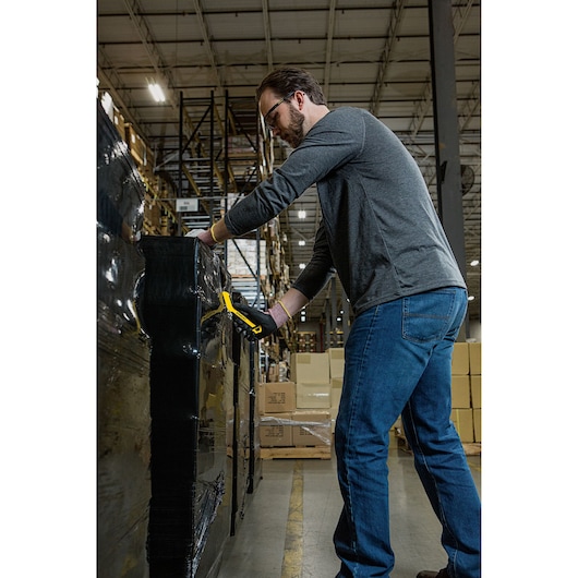 STANLEY STHT10357-1 utility knife used to cut plastic wrap on pallet in warehouse setting.