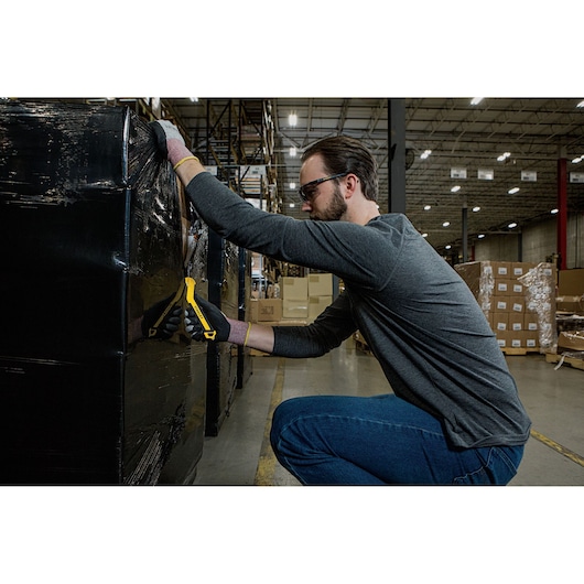STANLEY STHT10357-1 utility knife cutting black wrap on pallet in warehouse, side view.