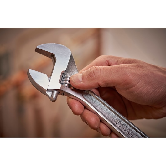 STANLEY STHT13121-0 adjustable wrench held in hand, silver finish, close-up photo.
