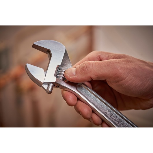 STANLEY STHT13156-0 adjustable wrench held in hand, close-up showing metal finish and jaw adjustment.