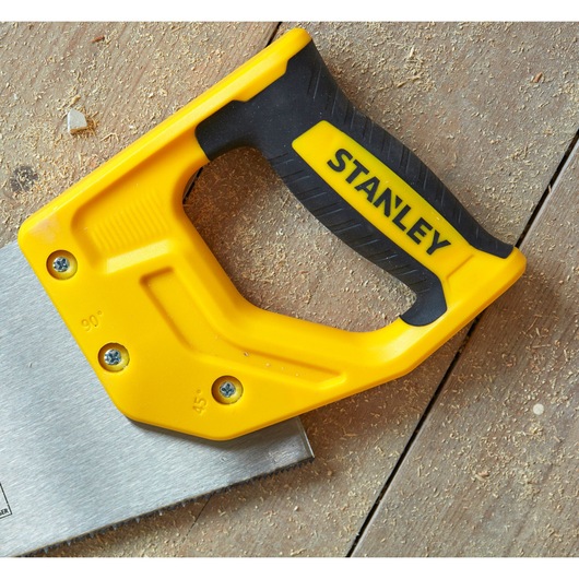 STANLEY STHT20369-1 handsaw with yellow and black handle, photographed on a wooden surface with sawdust.