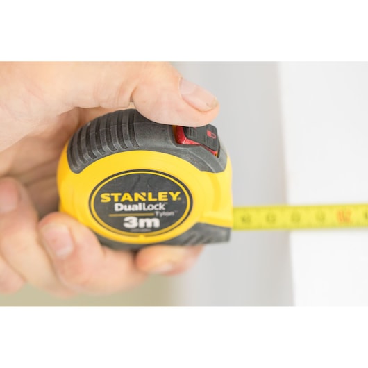 Photo of STANLEY STHT36802-0 tape measure DualLock 3m yellow casing in hand, tape extended.