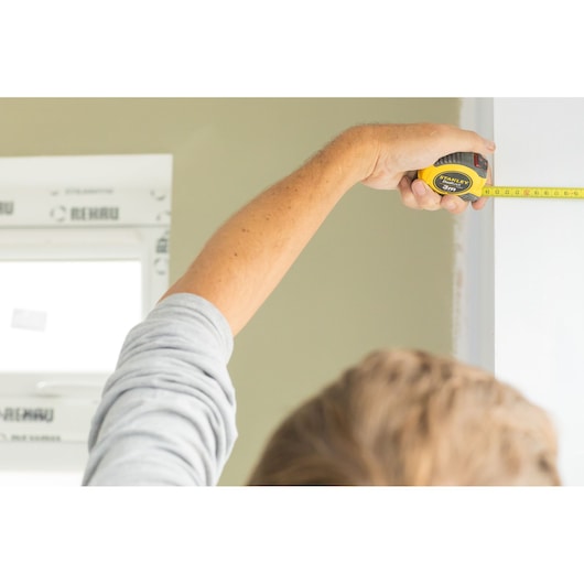 Photo of STANLEY STHT36802-0 tape measure in use measuring a doorway indoors.