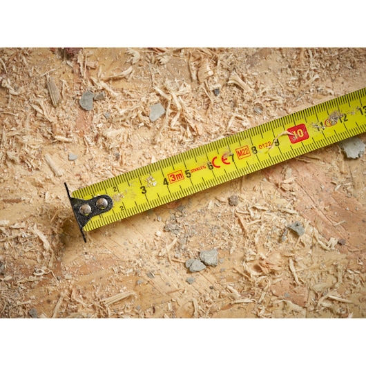 STANLEY STHT37230-0 yellow tape measure close-up on wood with sawdust, photography