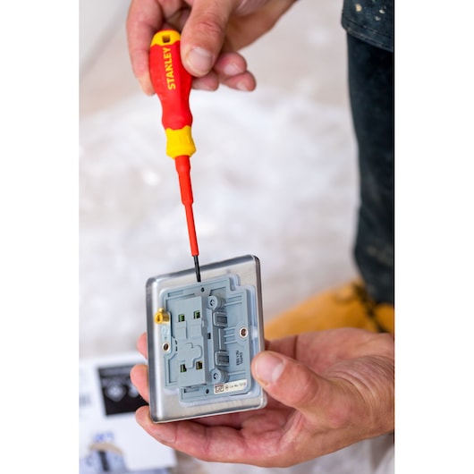 Photo of STANLEY STHT60032-0 insulated screwdriver in use on an electrical outlet, close-up view.