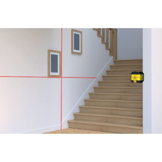 STANLEY STHT77498-1 laser level projecting red lines onto stair wall, photography angle from side.