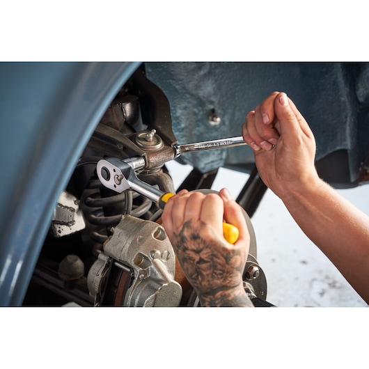 Photo of STANLEY STMT82831-1 ratchet and socket wrench in use on car suspension, close-up hands working.