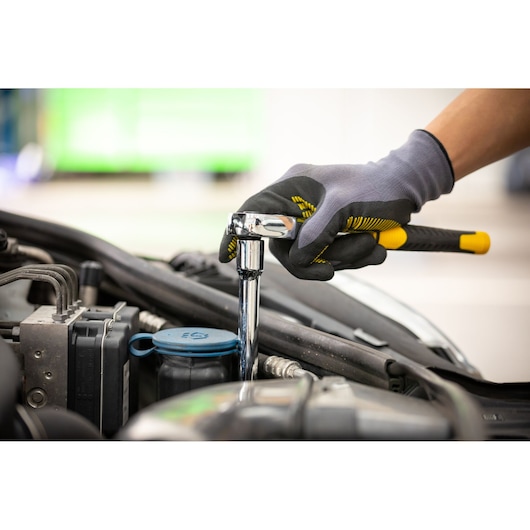 STANLEY STMT86006-0 ratchet wrench used for car engine maintenance, close-up of gloved hand holding tool.