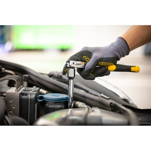 STANLEY STMT86206-0 ratchet wrench used on car engine, gloved hand grip, side angle, automotive tool.