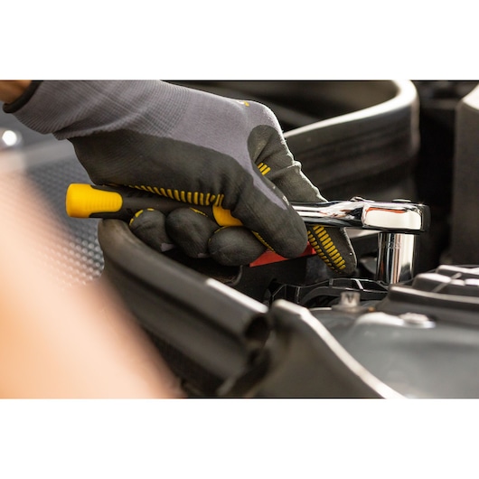 STANLEY STMT86306-0 ratchet wrench used by gloved hand near engine, close-up photography.