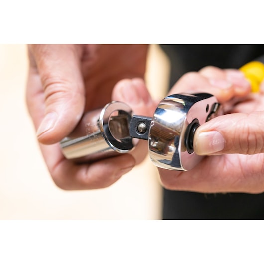 STANLEY STMT86512-0 ratchet socket tool close-up, hands attaching chrome socket, photography category.