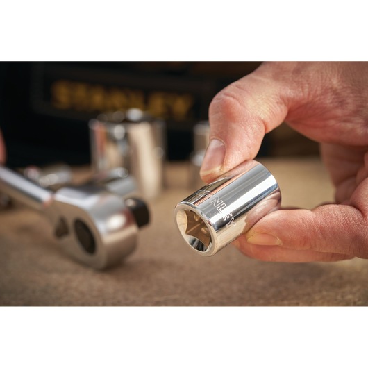 STANLEY STMT86515-0 socket held by hand with ratchet tool, close-up photography on work surface.
