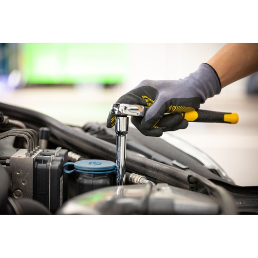 Photo of STANLEY STMT88941-0 ratchet wrench used on car engine, worker wearing gloves.