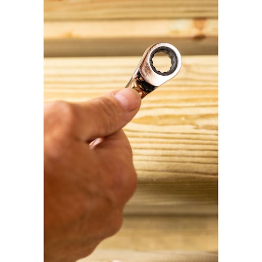 STANLEY STMT89908-0 ratcheting wrench held by hand against light wood background, close-up photography.