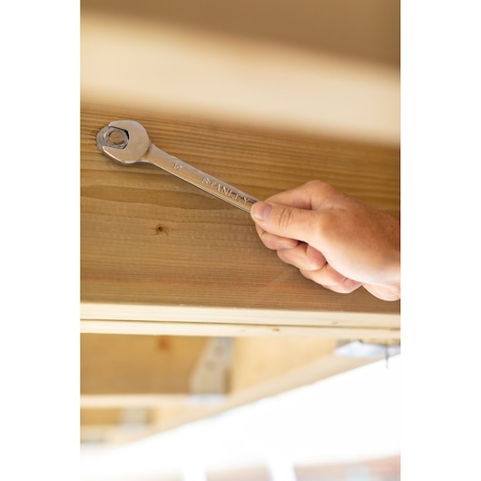 STANLEY STMT89915-0 wrench in use tightening a bolt on wood, close-up photography.