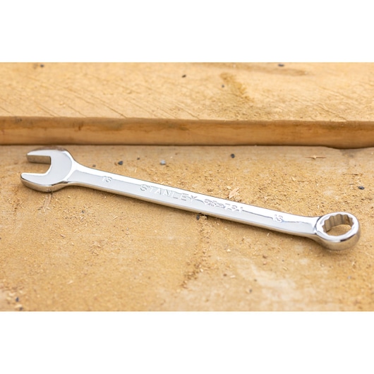 STANLEY STMT95910-0 combination wrench, silver finish, lying diagonally on a sandy wooden surface.