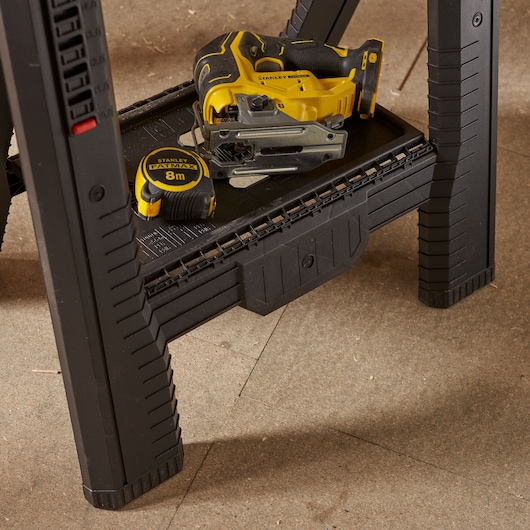 Photo of STANLEY STST1-70559 black plastic sawhorse with storage tray, tape measure, and jigsaw.