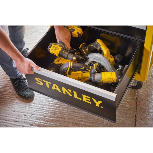 Photo of STANLEY STST74305-1 drawer filled with STANLEY power tools, shown from above on a workshop floor.