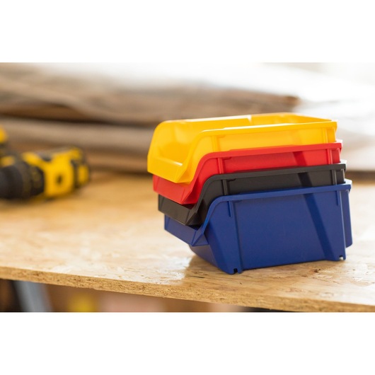 STANLEY STST82740-1 stackable plastic storage bins in yellow, red, black, blue on a workbench, side angle.