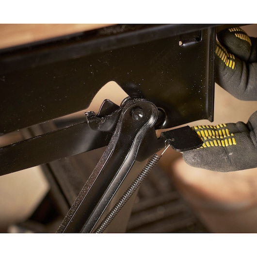 STANLEY STST83800-1 photography of black metal hinge with spring being adjusted by gloved hand.