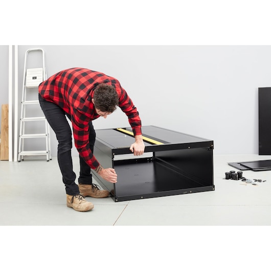 STANLEY STST97957-1 cabinet assembly in progress, black steel cabinet on floor with hardware nearby.