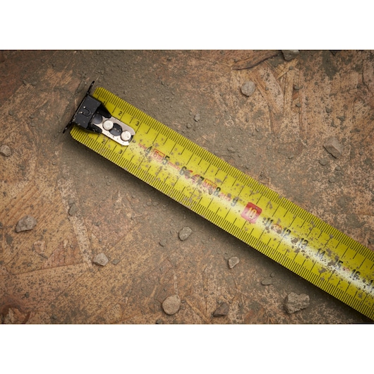 STANLEY XTHT0-33671 yellow tape measure on rough, dusty ground, close-up photography.