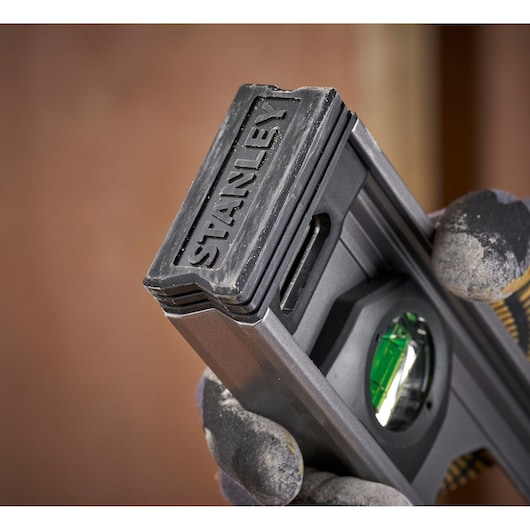 Photo of STANLEY XTHT1-42131 level tool held in gloved hand with visible green vial.